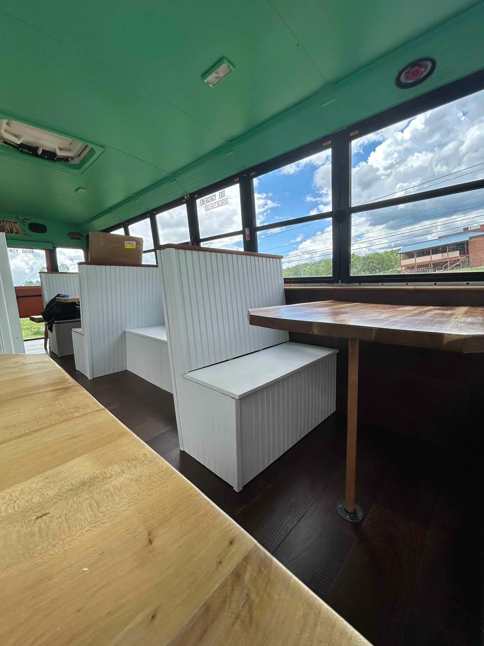 A wood-topped booth beside big bus windows looking out over the hills