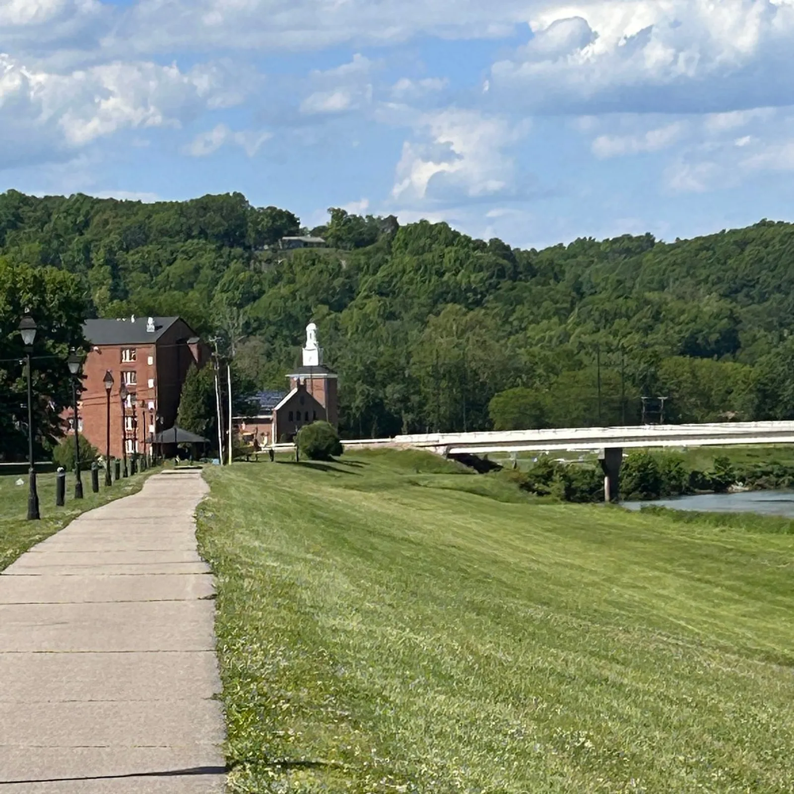 The paved Hockhocking rail-trail winding past red-brick buildings toward the river bridge and green Appalachian hills